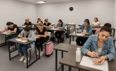 Tre elever fokuserade p&aring; nagelutbildning i klassrum med handledare.