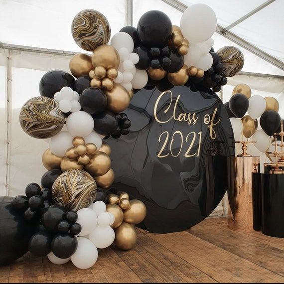 Dekorationer för studentskiva med ballongbåge i guld och svart.
