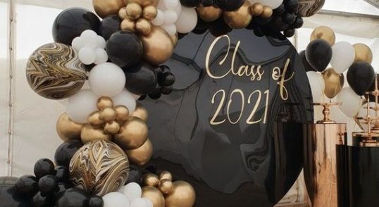 Dekorationer för studentskiva med ballongbåge i guld och svart.