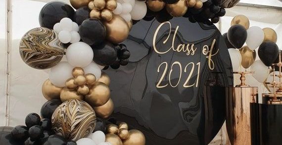 Dekorationer för studentskiva med ballongbåge i guld och svart.